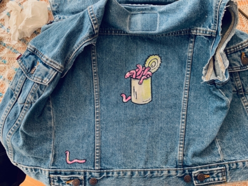 A blue denim vest with a can of worms painted on it